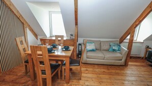 Une pièce de style loft avec une table à manger, des chaises, un canapé et un plancher en bois.