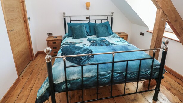 Une chambre avec un plafond en pente, un cadre de lit en métal et un plancher en bois.