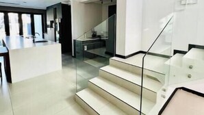 Un interior moderno con una escalera que lleva a un nivel superior, una zona de cocina y un espacio para comer.