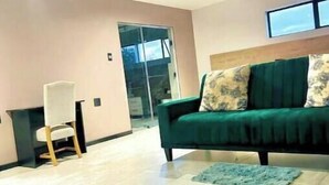 Un salón amplio con un sofá verde, una mesita y un ventanal grande.