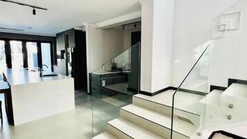 Ein modernes Interieur mit einer Treppe zu einer zweiten Etage, einer Küchenzeile und einem Essbereich.