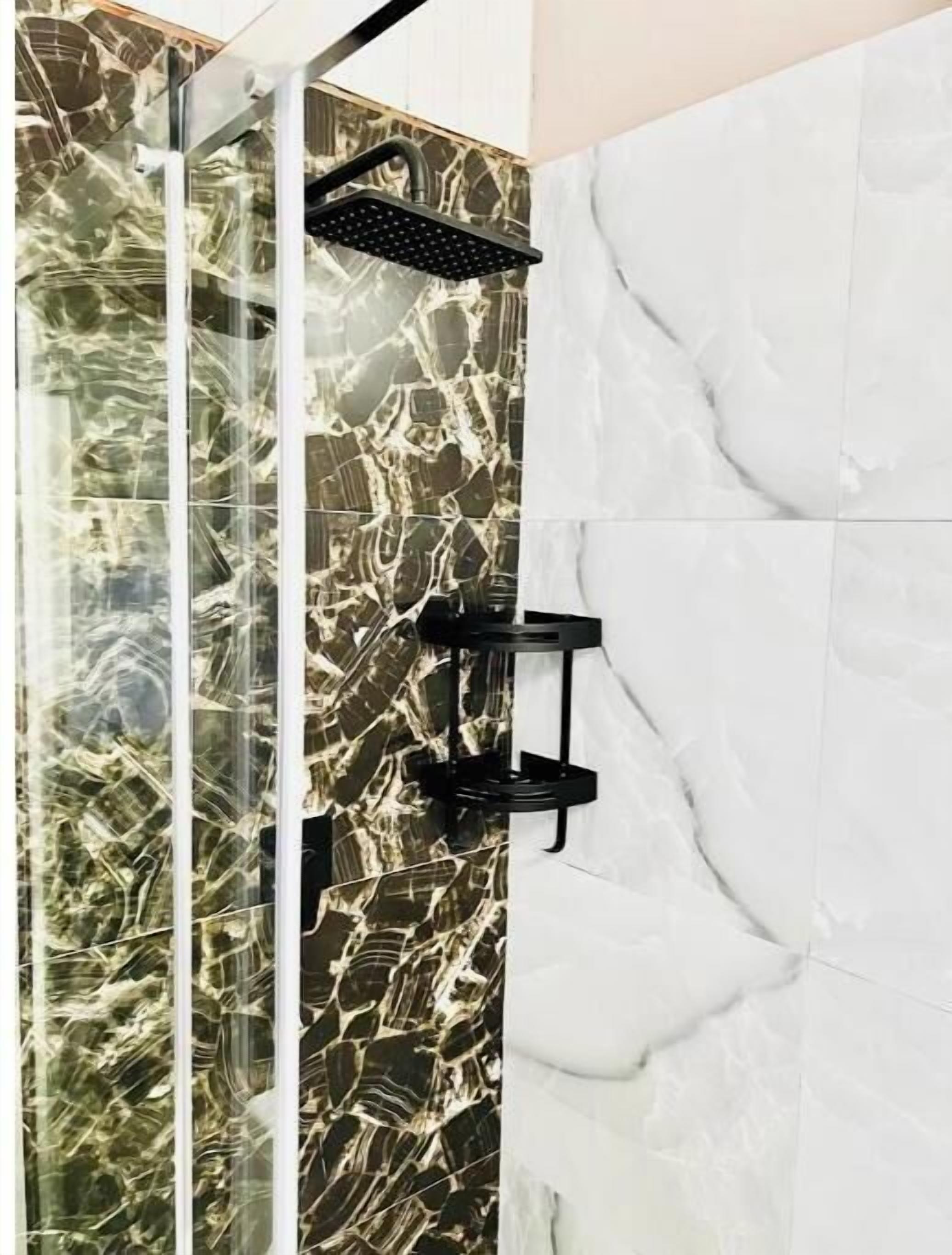 A shower with a glass enclosure and a marble wall.