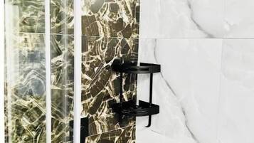 A shower with a glass enclosure and a marble wall.
