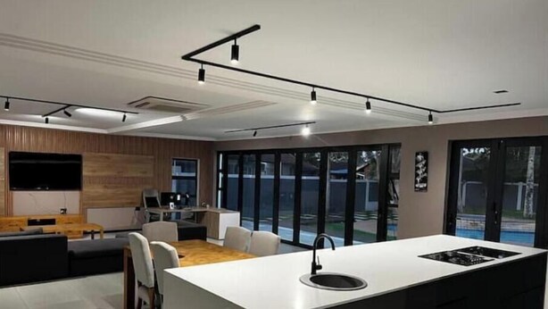Een moderne keuken met een centraal eiland, een eethoek met stoelen en een groot raam dat uitzicht biedt op de omgeving.
