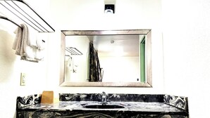 A bathroom with a marble sink, a mirror, and a towel rack. - Southern Comfort Motel (Birmingham)