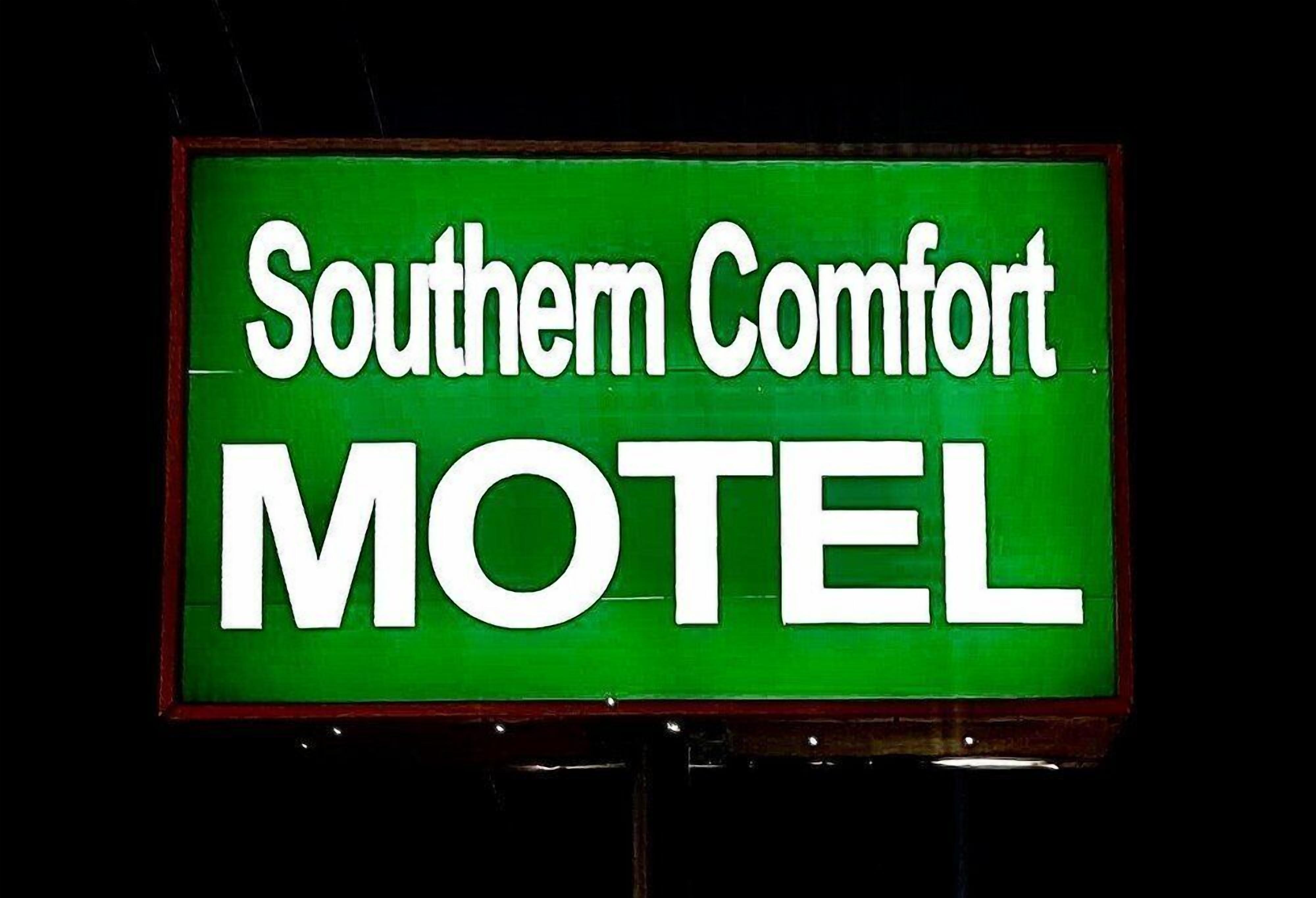 A motel sign with the name 'Southern Comfort MOTEL' in white letters on a green background.