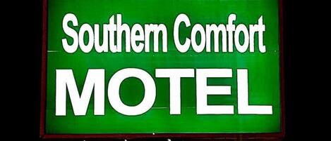 A motel sign with the name 'Southern Comfort MOTEL' in white letters on a green background.