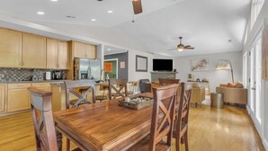 A spacious kitchen with wooden cabinets, a dining area with a wooden table and chairs, and a ceiling fan.