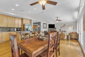 Una cocina amplia con armarios de madera, un comedor con una mesa y sillas de madera, y un ventilador de techo.