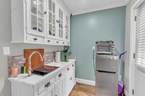 Una cocina con armarios blancos, horno empotrado y salpicadero de azulejos.