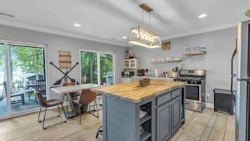 Een moderne keuken met een centraal eiland, inbouwapparatuur en een eethoek met stoelen.