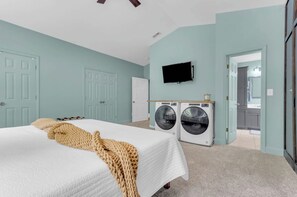 Un dormitorio con cama, lavadora y televisor.