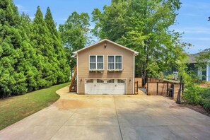 A single-story house with a garage, surrounded by a well-maintained lawn and tall trees.