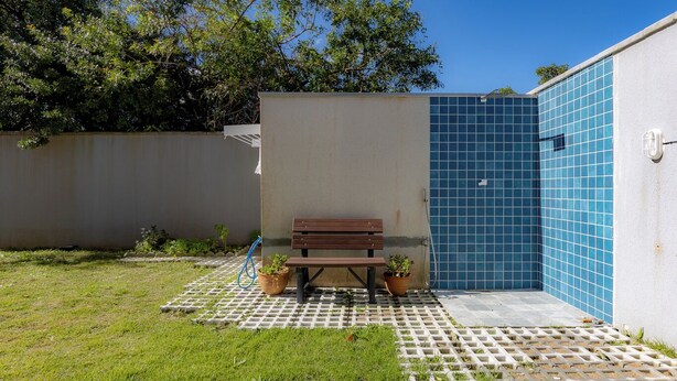 Un pequeño espacio al aire libre con un banco, plantas en macetas y un muro de azulejos.