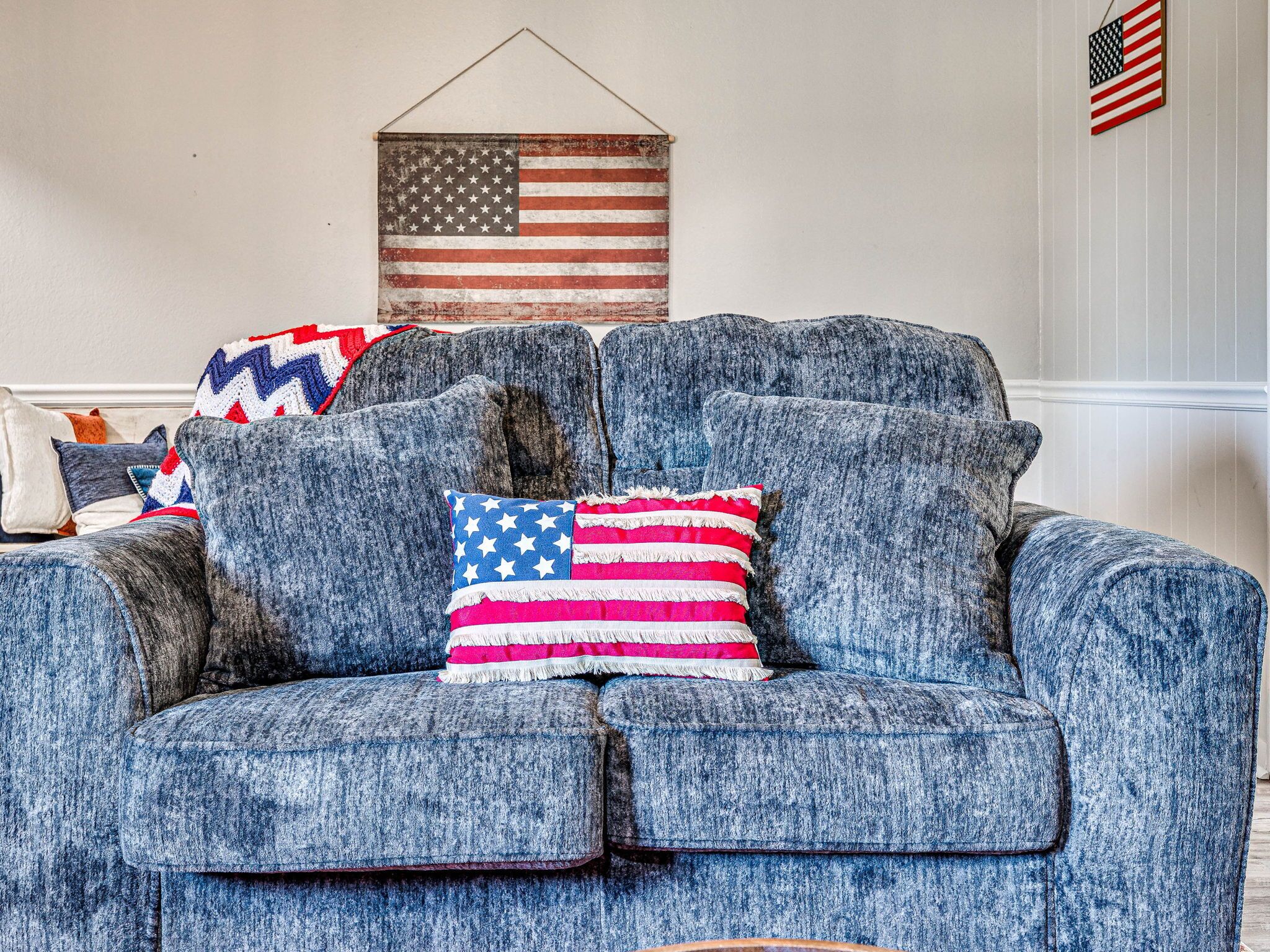 A blue sofa with two pillows, one with an American flag design.