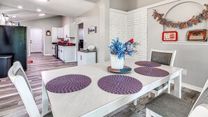 Ein Essbereich mit einem weißen Tisch, violetten Untersetzern und einer Blumenvase.