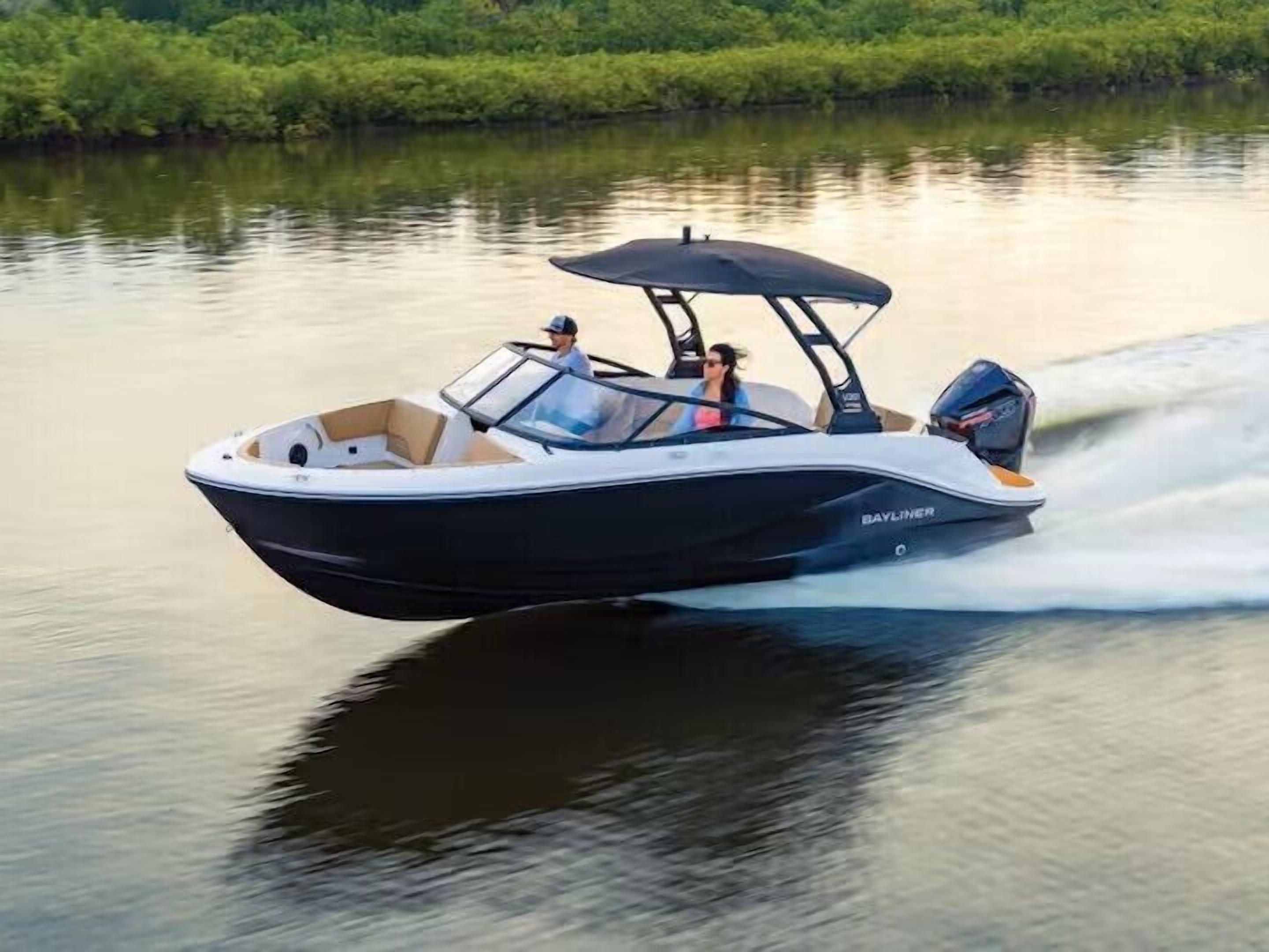 A speedboat with a canopy, two passengers, and a wake behind it.