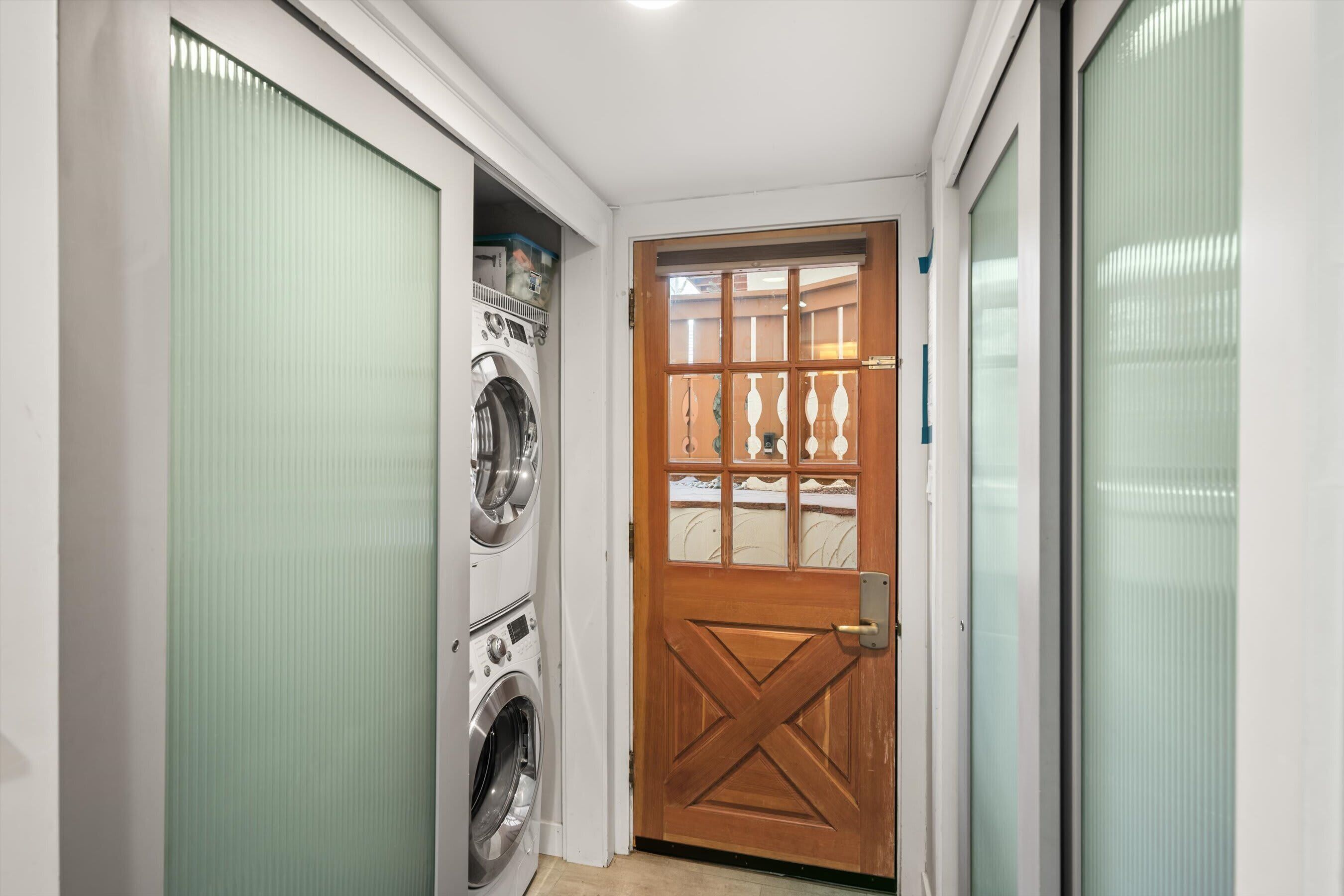 A laundry room with a wooden door and a washing machine.