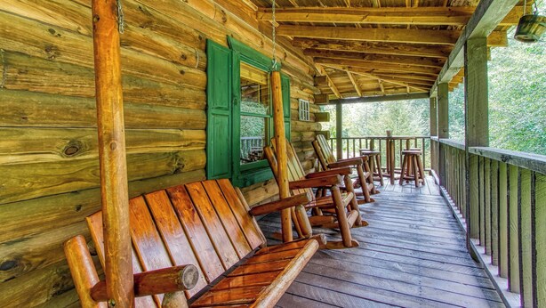 A wooden cabin with a porch, wooden benches, and a green door. - Summer Sale! Rustic Romance Classic American Cabin Vibes! (Sevierville)