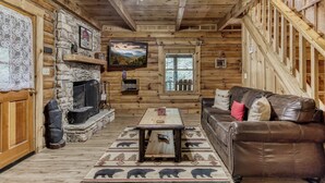 A log cabin interior with a stone fireplace, wooden ceiling, and a leather sofa. - Summer Sale! Rustic Romance Classic American Cabin Vibes! (Sevierville)