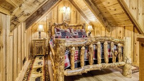 A rustic wooden room with a bed, a nightstand, and a lamp. - Summer Sale! Rustic Romance Classic American Cabin Vibes! (Sevierville)