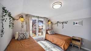 A bedroom with two beds, a nightstand, a window with curtains, and a wall-mounted light fixture. - Wichita Getaway • Popcorn • Fast Wi-Fi & free Coffee bar (Wichita)
