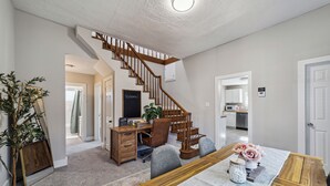 A spacious living room with a wooden staircase, a dining area with a table set for two, and a kitchen in the background. - Wichita Getaway • Popcorn • Fast Wi-Fi & free Coffee bar (Wichita)