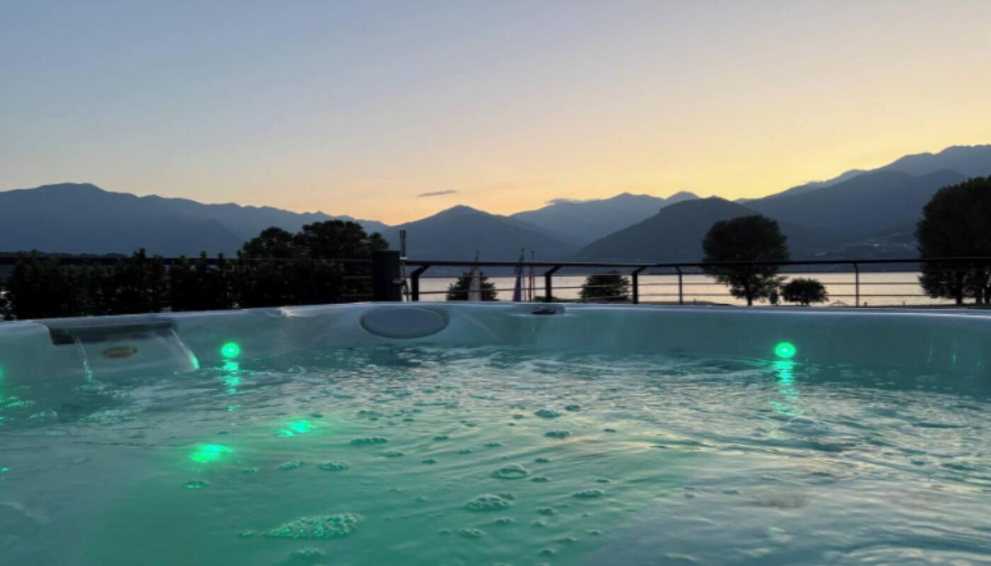 A hot tub with a view of mountains and a lake at dusk.