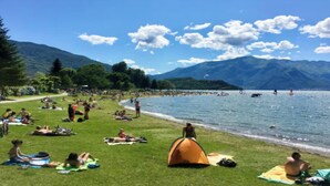A lakeside park with grassy areas, a tent, and people relaxing.
