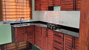 A kitchen with wooden cabinets, a black countertop, and a window with blinds. - Fabulous 1- self contained bedroom apartment with AC in Pwani Region (Kibaha)
