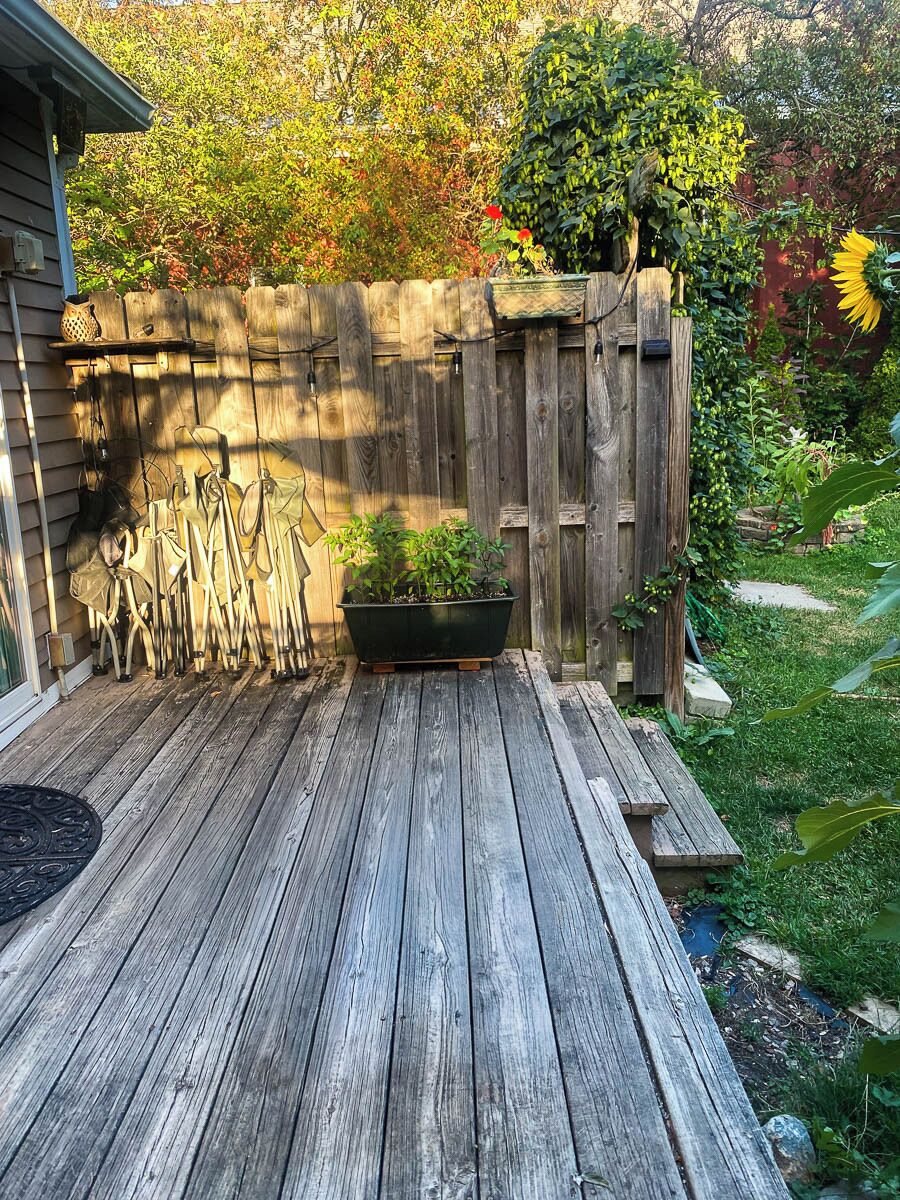 A wooden deck with a potted plant and a wooden fence.