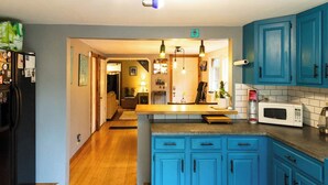 Cocina con gabinetes azules, encimera de madera y un microondas.