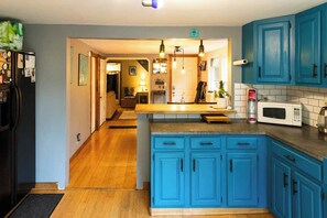 Cocina con gabinetes azules, encimera de madera y un microondas.