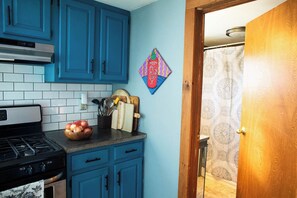 Una cocina con armarios azules, estufa a gas y un adorno en la pared.