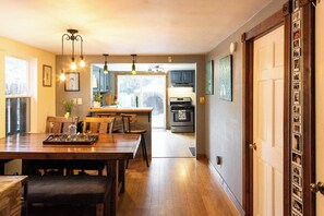 A kitchen with wooden cabinets, a dining table, and pendant lighting.