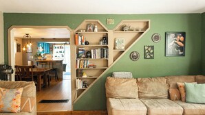 Una sala de estar con una pared verde, un sofá, una mesa de centro y una estantería.
