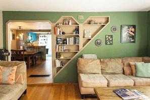 Una sala de estar con una pared verde, un sofá, una mesa de centro y una estantería.