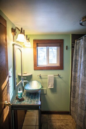 A bathroom with a sink, mirror, window, and shower curtain.