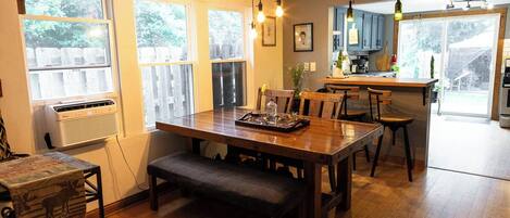 A dining area with a wooden table, benches, and a kitchen in the background.