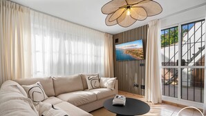 Una sala moderna con un amplio sofá modular, una mesa de centro redonda negra y un televisor montado en la pared con vistas panorámicas.