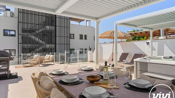 Un área de comedor al aire libre moderna con terraza, mobiliario de mimbre y una mesa lista para dos.