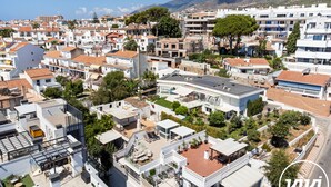 Zona residencial con casas modernas, una piscina en la azotea y montañas al fondo.