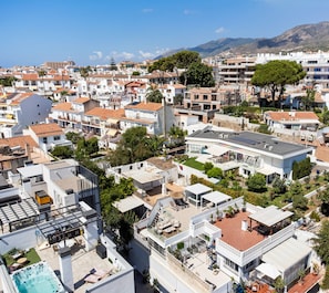 Zona residencial com casas modernas, uma piscina no terraço e montanhas ao fundo.