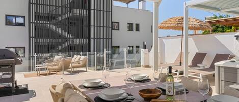 Un área de comedor al aire libre moderna con terraza, mobiliario de mimbre y una mesa lista para dos.