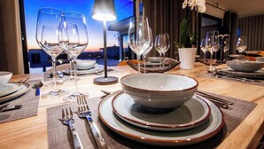 A dining table set with plates, bowls, glasses, and cutlery, with a view of the cityscape at dusk. - Perfect villa Stressless with beautiful pool in charming Smoković (Smoković)