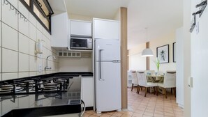 A modern kitchen with a gas stove, white cabinets, a microwave, and a refrigerator. - Apt Charming Sea View in Canasvieiras Emp2201 (Florianópolis)