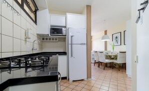 A modern kitchen with a gas stove, white cabinets, a microwave, and a refrigerator. - Apt Charming Sea View in Canasvieiras Emp2201 (Florianópolis)