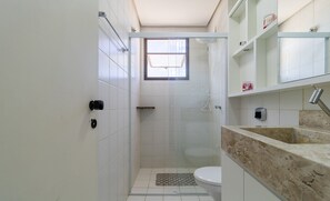 A bathroom with a shower, toilet, and a sink with a marble countertop. - Apt Charming Sea View in Canasvieiras Emp2201 (Florianópolis)