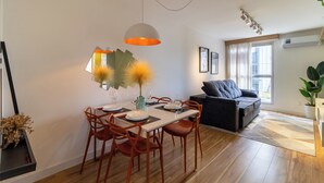 A modern living room with a dining area, featuring a sofa, a dining table with chairs, and a pendant light.