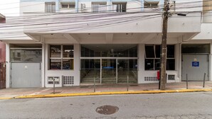 A building with a covered entrance, multiple windows, and a visible staircase leading to an upper floor.